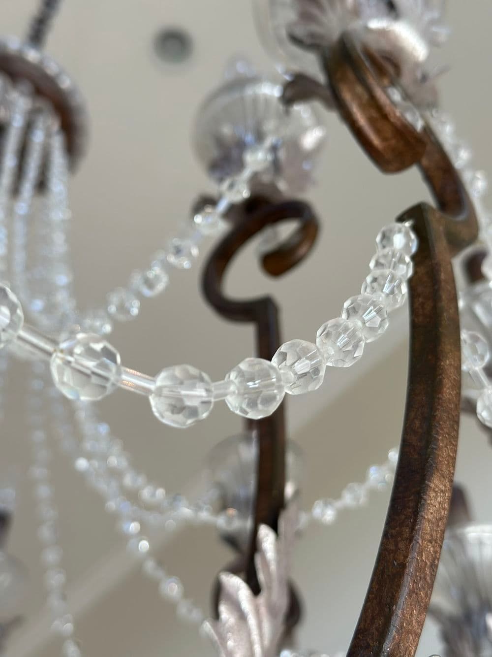 Elegant chandelier with crystal beads and ornate metalwork, showcasing intricate design.